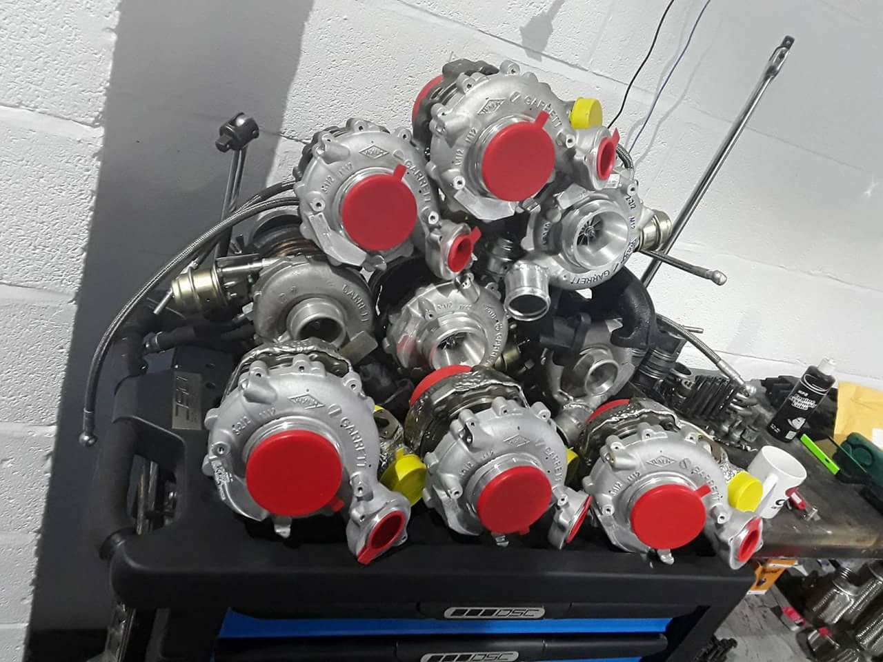 A stack of turbochargers with red protective caps on a tool chest