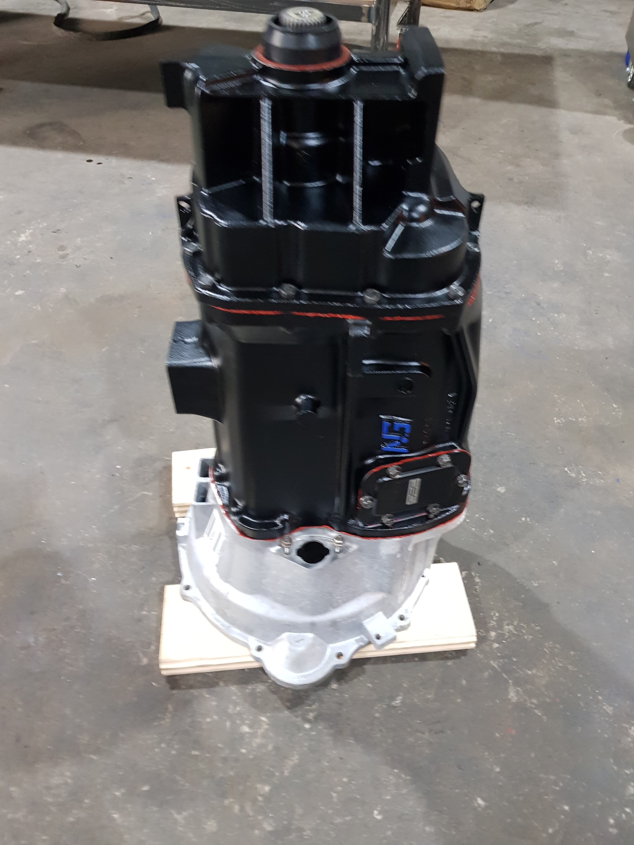 A rebuilt gearbox with a black-painted casing standing on a wooden pallet in the DSC workshop